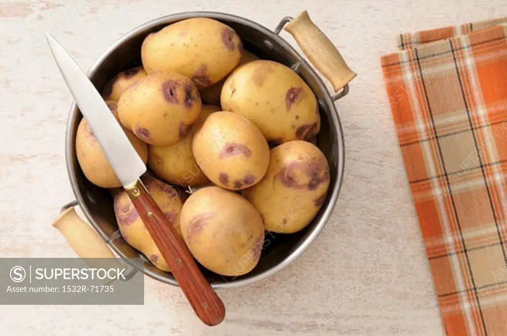 Potatoes in a colander with a knife