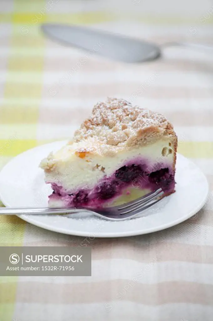 A slice of crumble-topped quark cake with blackberries