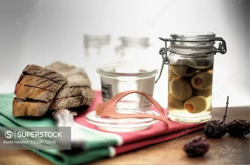 Pickled olives in a pickling jar with locking lid, sliced Farmer's bread next it