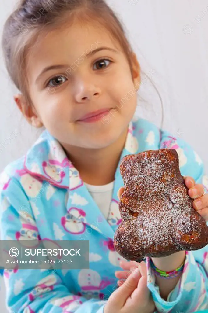 A girl holding up a bear-shaped carrot cake