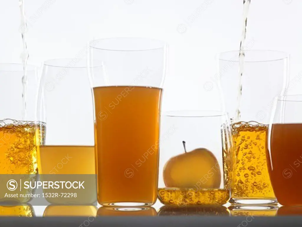 Assorted clear and cloudy apple juices in glasses