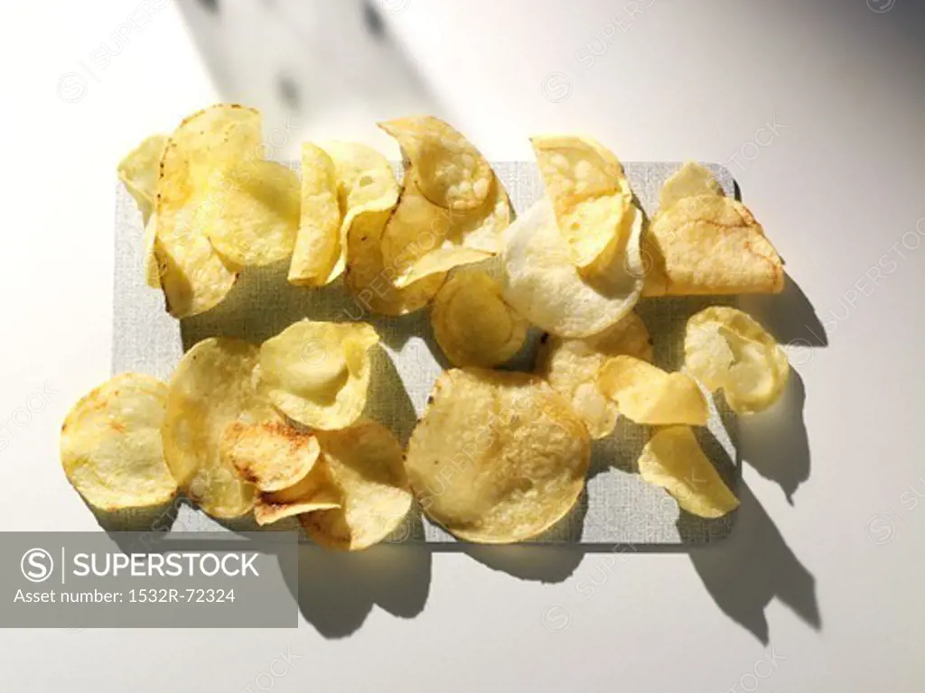 Potato crisps on a cutting board (view from above)