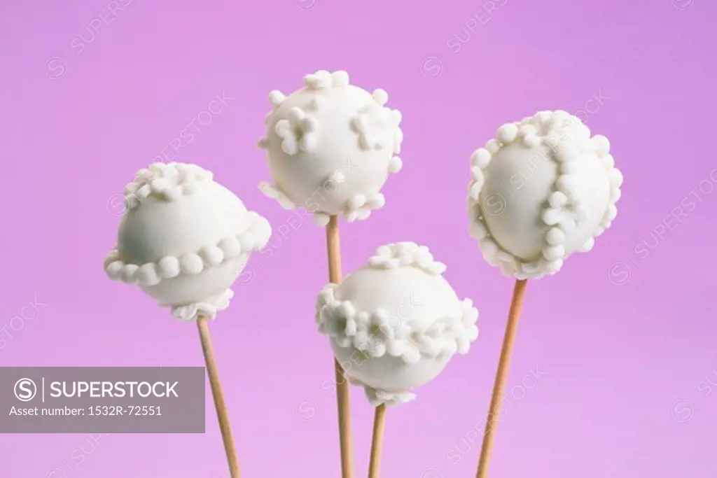 Vanilla cake pops with white icing against a purple background
