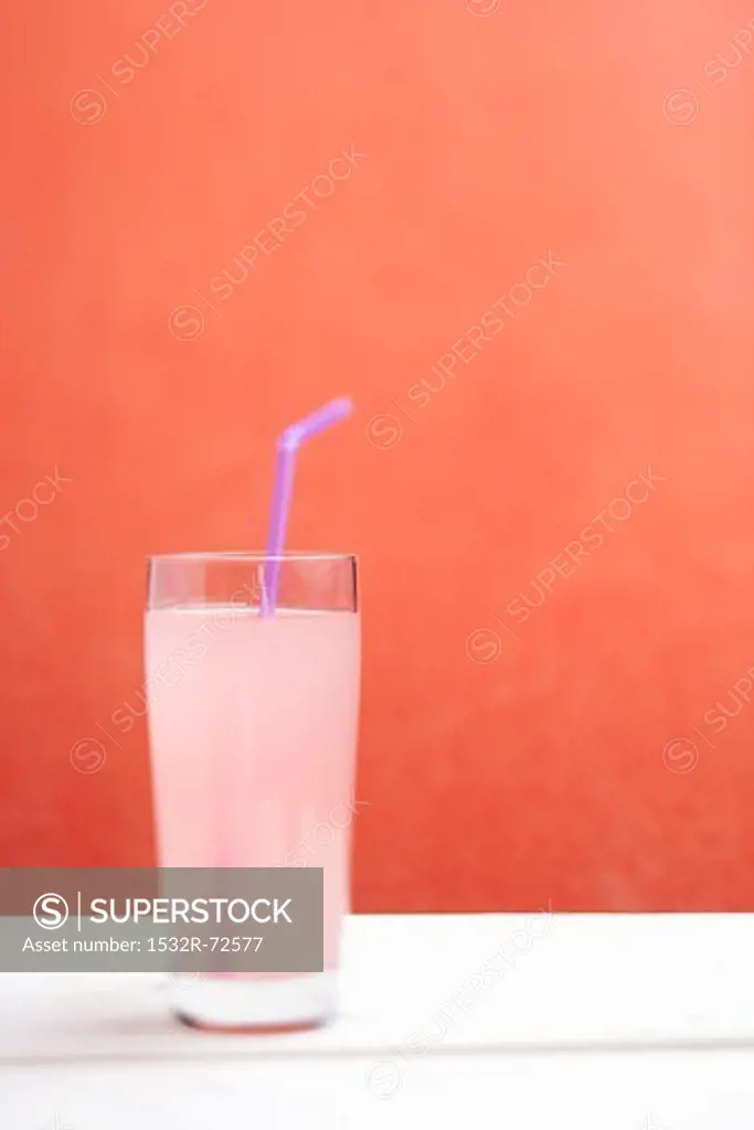 Rhubarb juice with a drinking straw in a glass