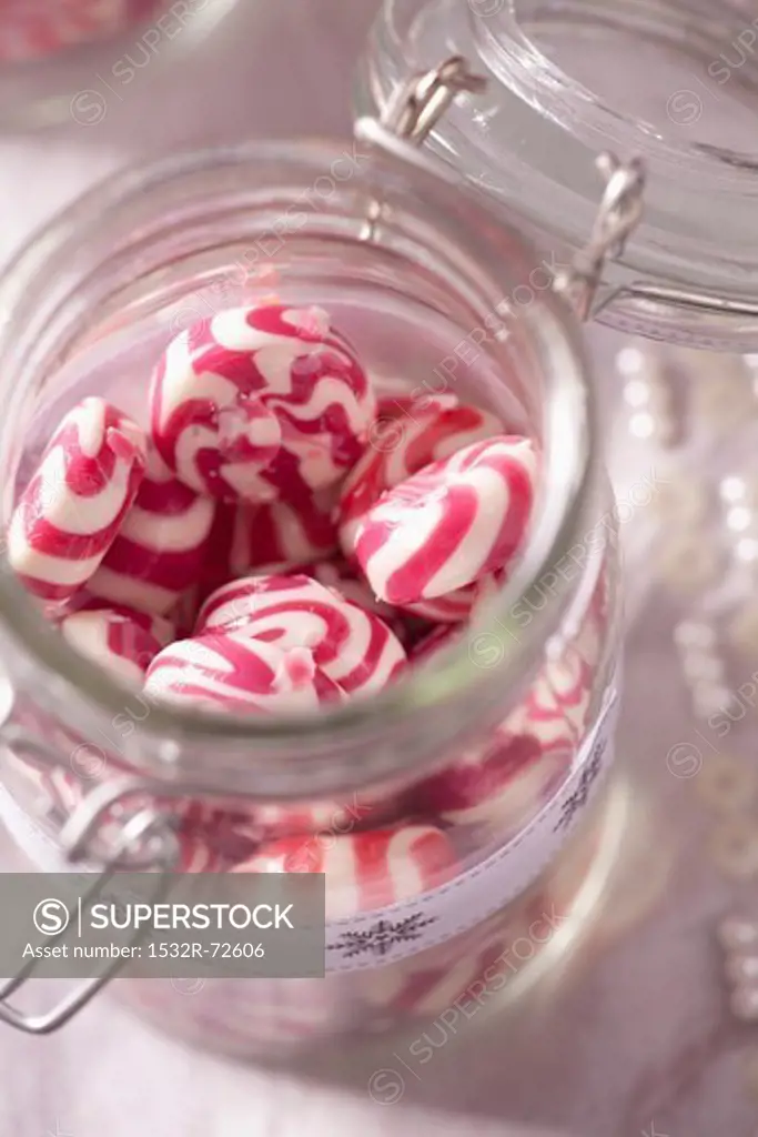 Red and white peppermint sweets in a storage jar