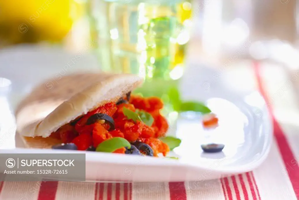 Grilled sandwich filled with tomatoes, black olives and basil