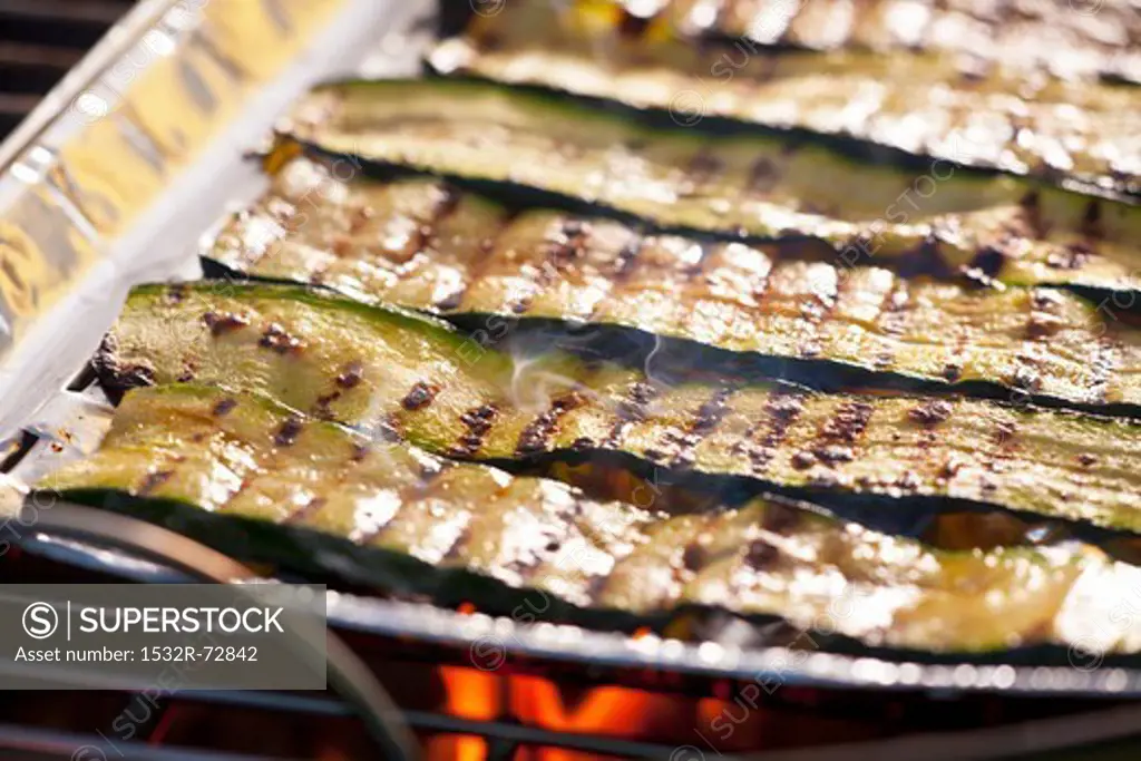 Courgette strips in an aluminium tray on a barbecue