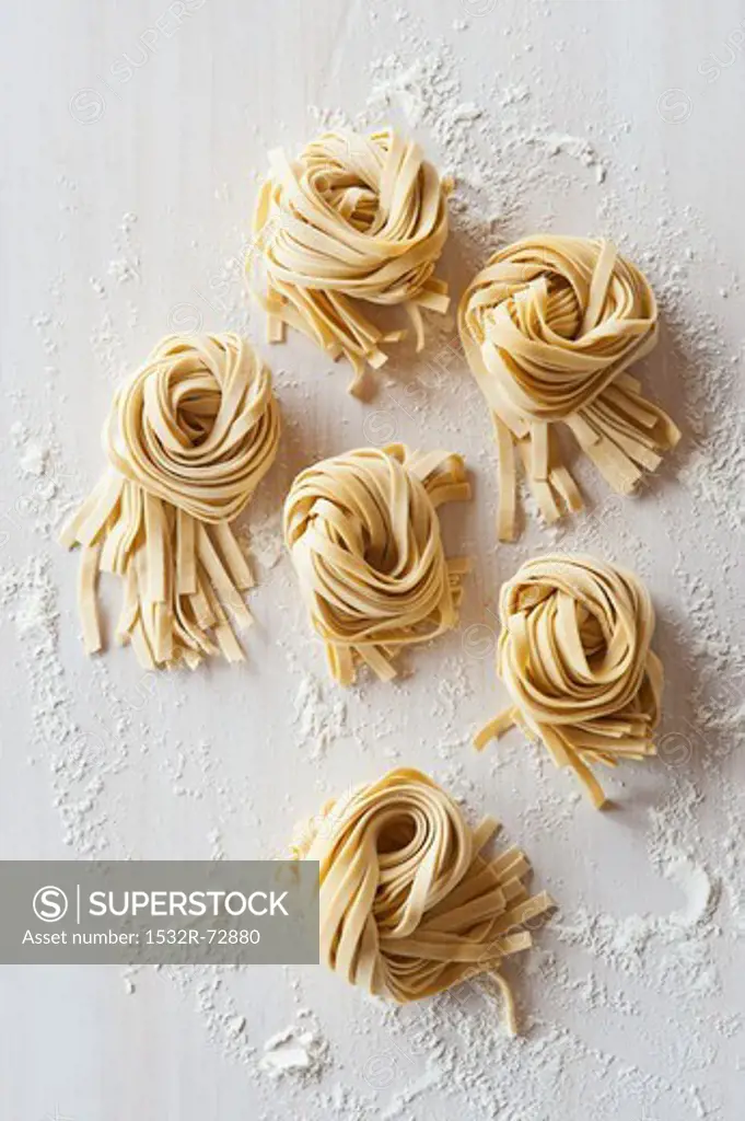 Nests of flat noodles on a floured worktop (view from above)