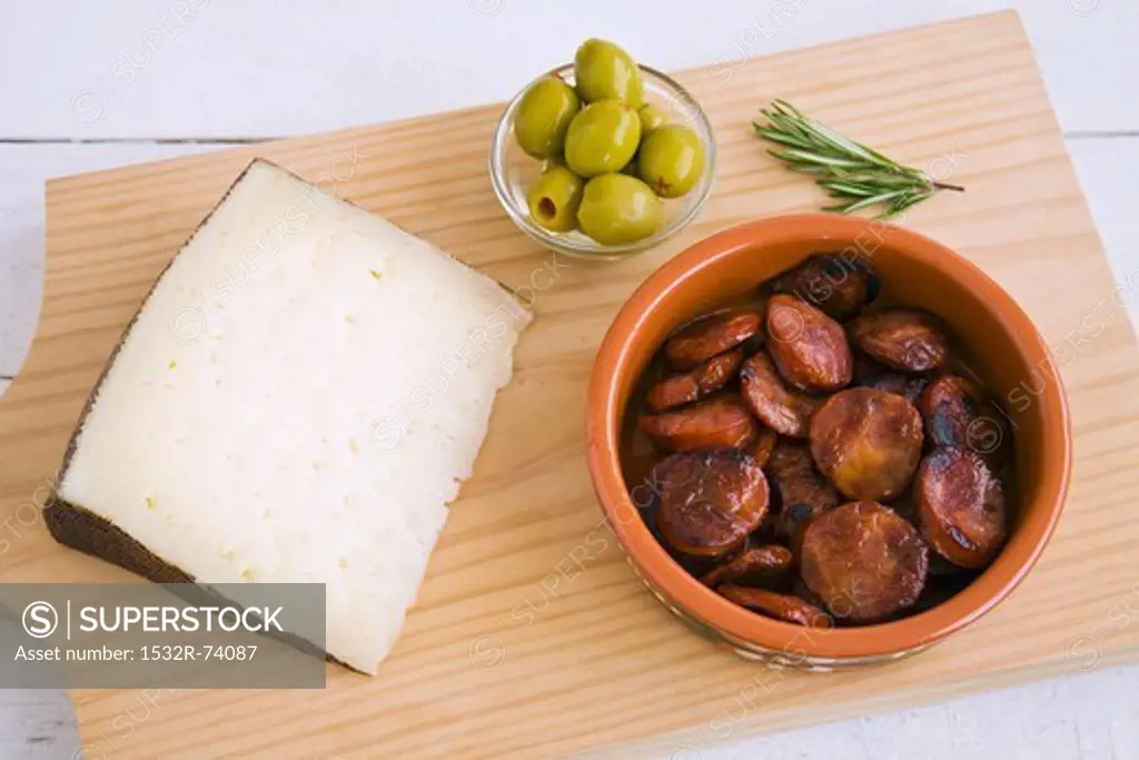 Manchego, fried chorizo slices and olives on a wooden board, 9/3/2013
