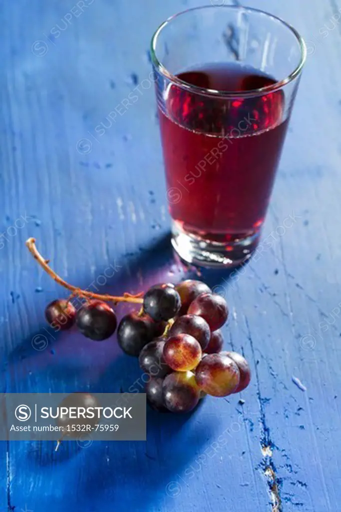 Red wine grapes and grape juice on a bllue wooden tabletop, 10/23/2013