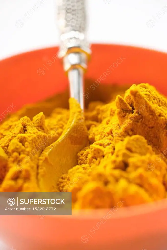 Turmeric in orange bowl with spoon