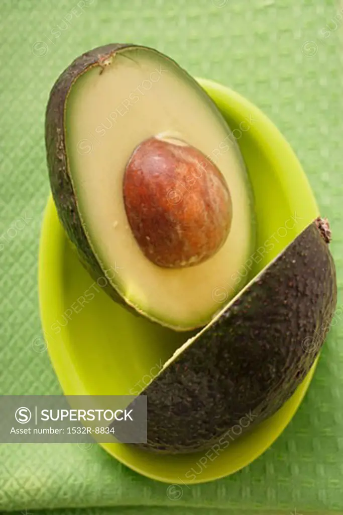 Avocado, halved, on green plate