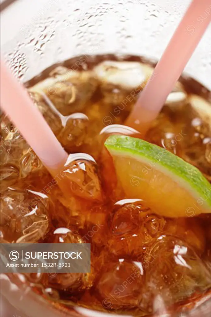 Cola with ice cubes and lemon (close-up)