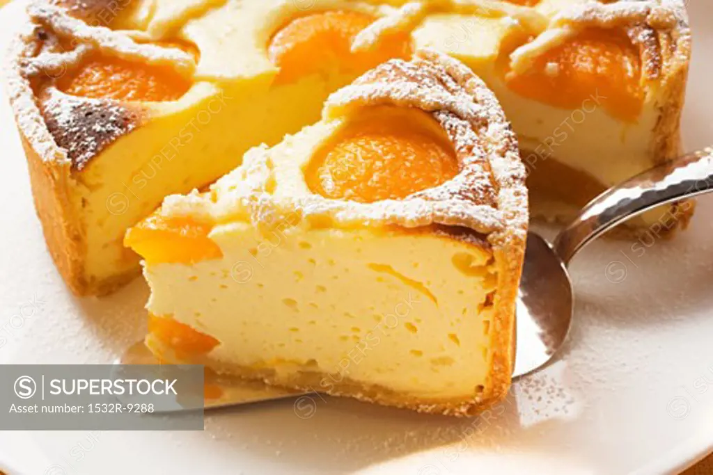 Piece of apricot cheesecake in front of cut cake