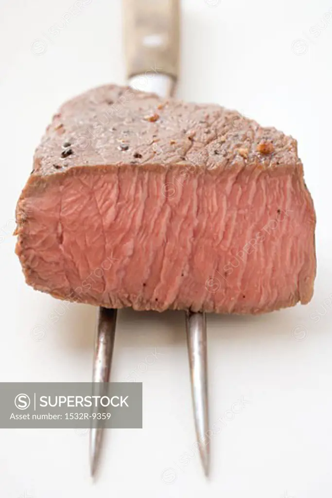 Beef steak, a piece cut off, on meat fork