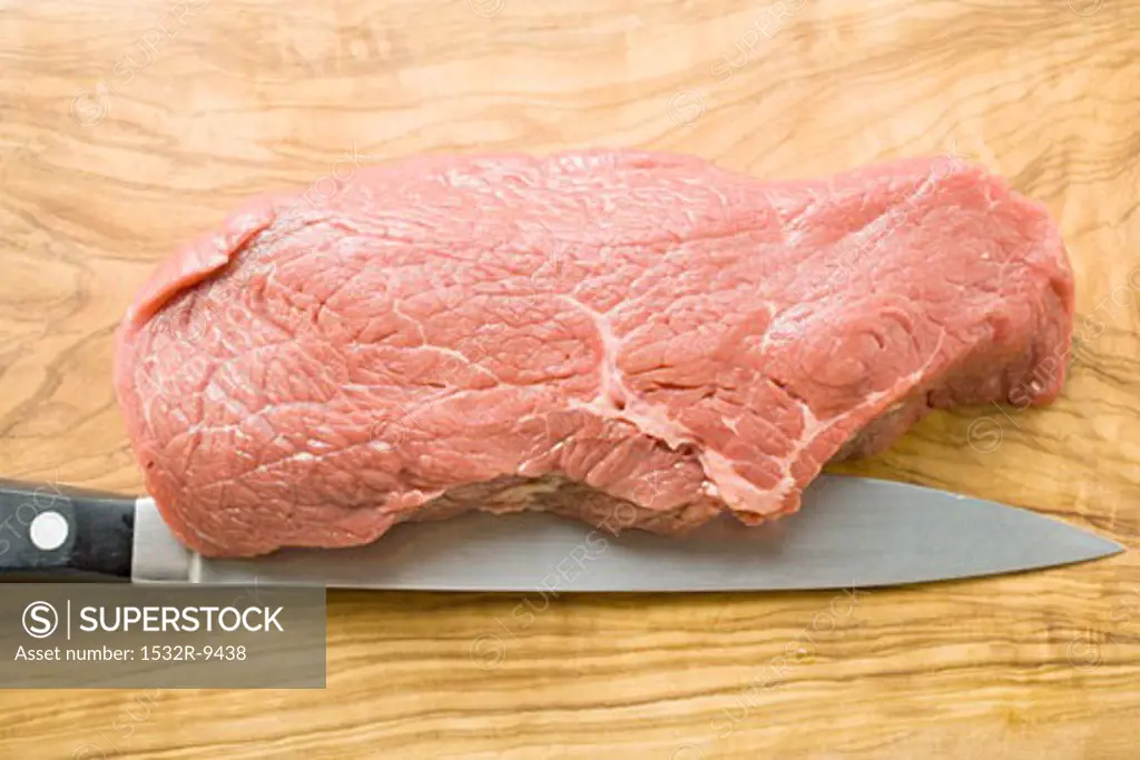 Beef sirloin with knife on chopping board