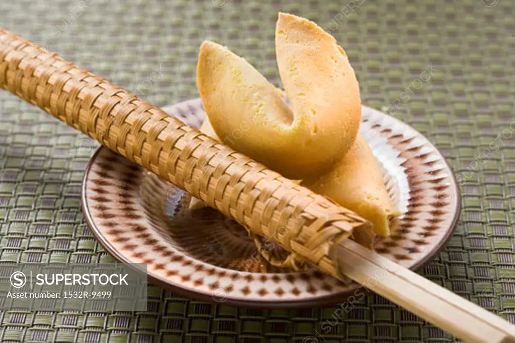 Fortune cookies and chopsticks in woven wrapper on plate