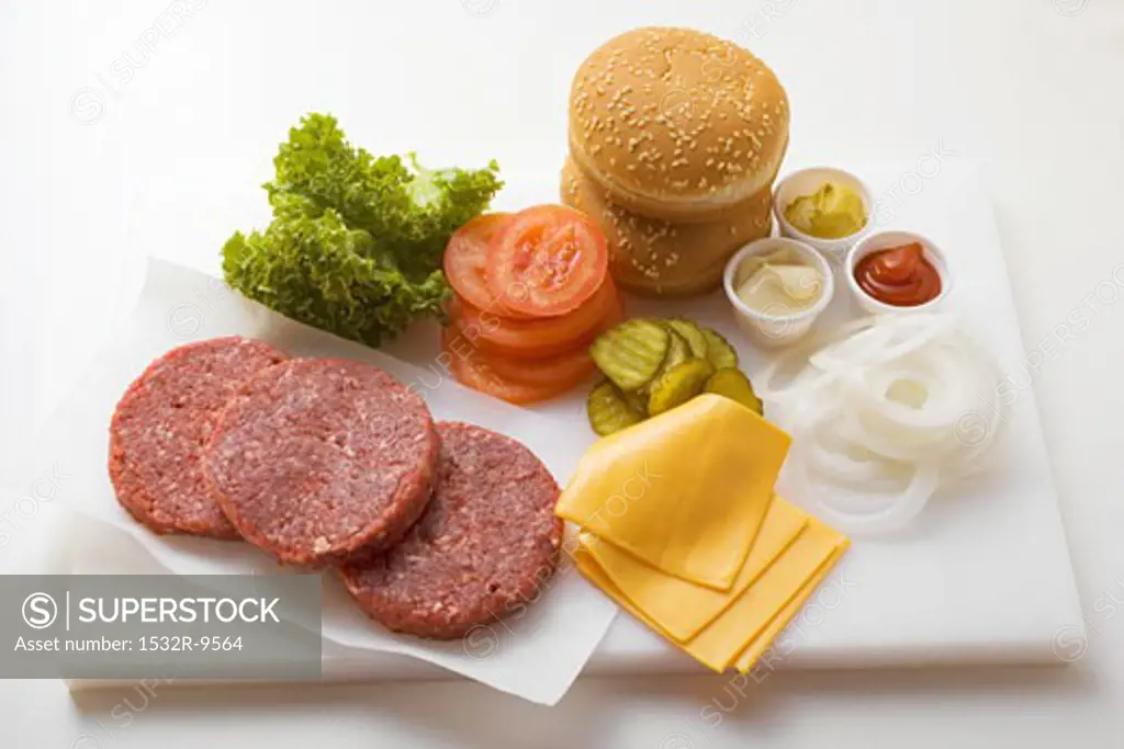 Ingredients for cheeseburgers on chopping board