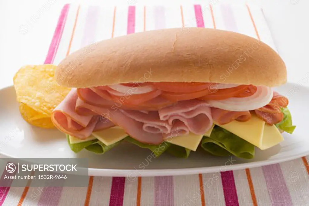 Ham, cheese, tomato and onion in sub sandwich with crisps