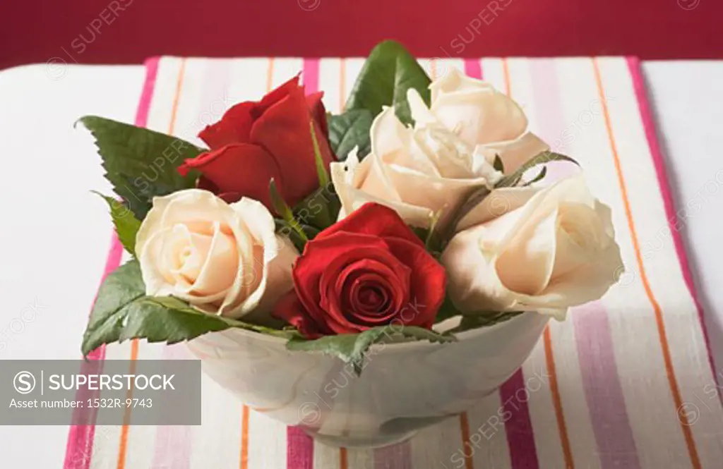 Roses in bowl on striped tablecloth