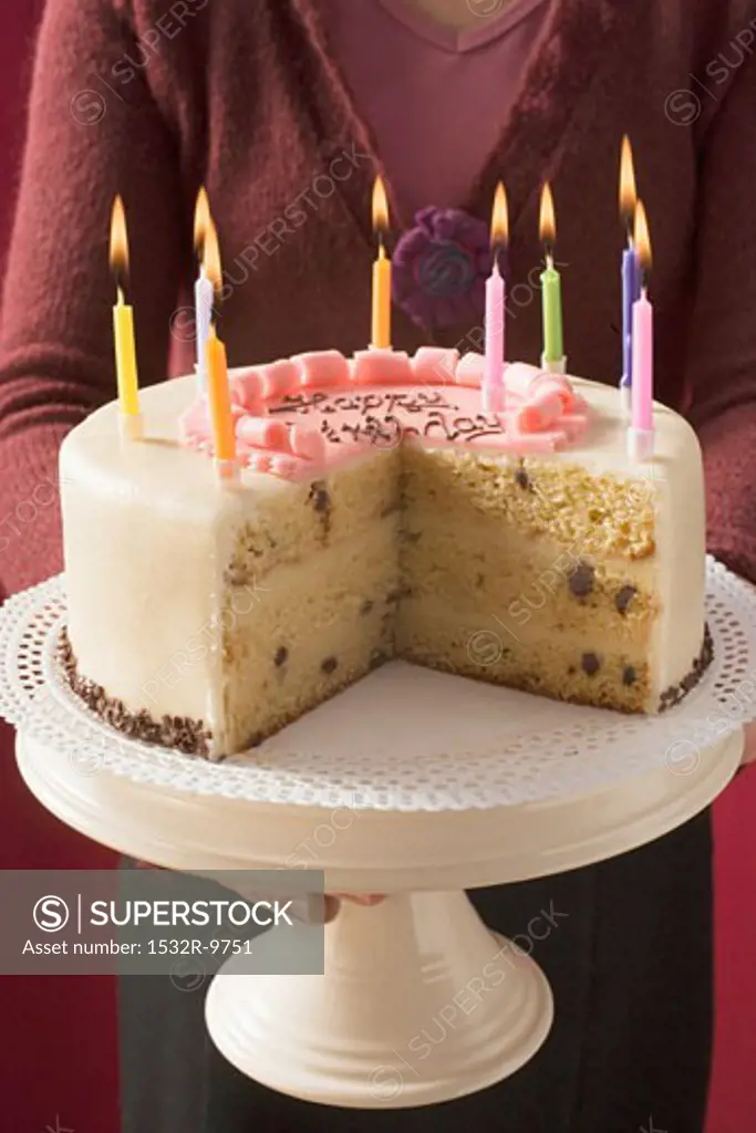 Woman serving birthday cake with burning candles
