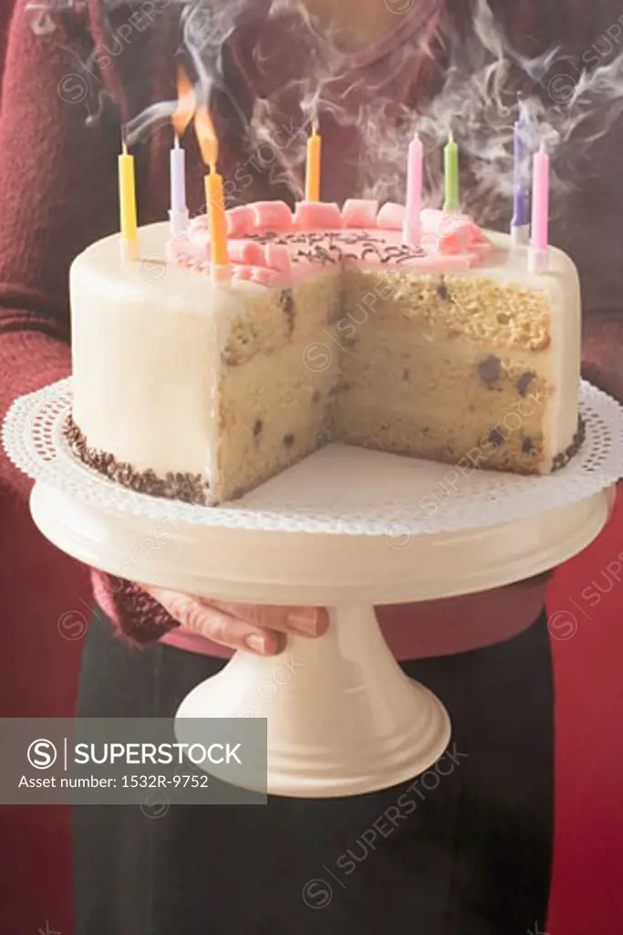 Woman serving birthday cake with blown-out candles