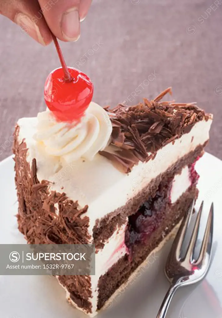 Decorating a piece of Black Forest gateau with cherry