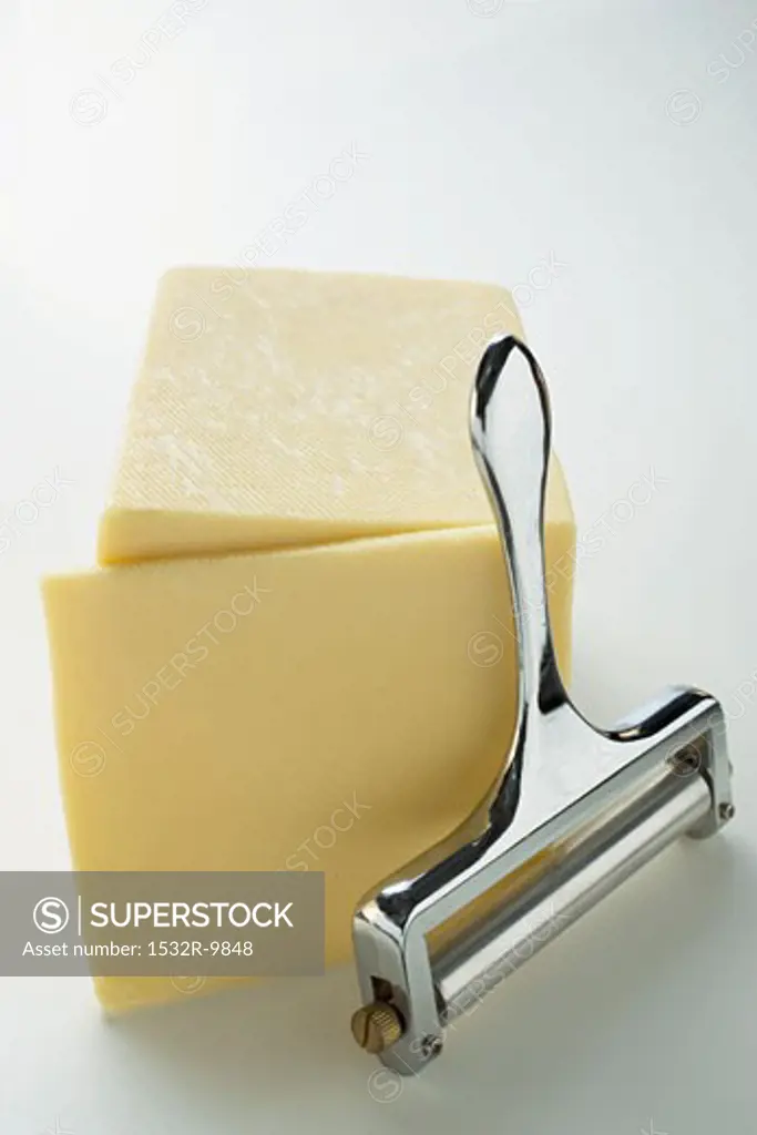 Semi-hard cheese with a slice cut and a cheese cutter