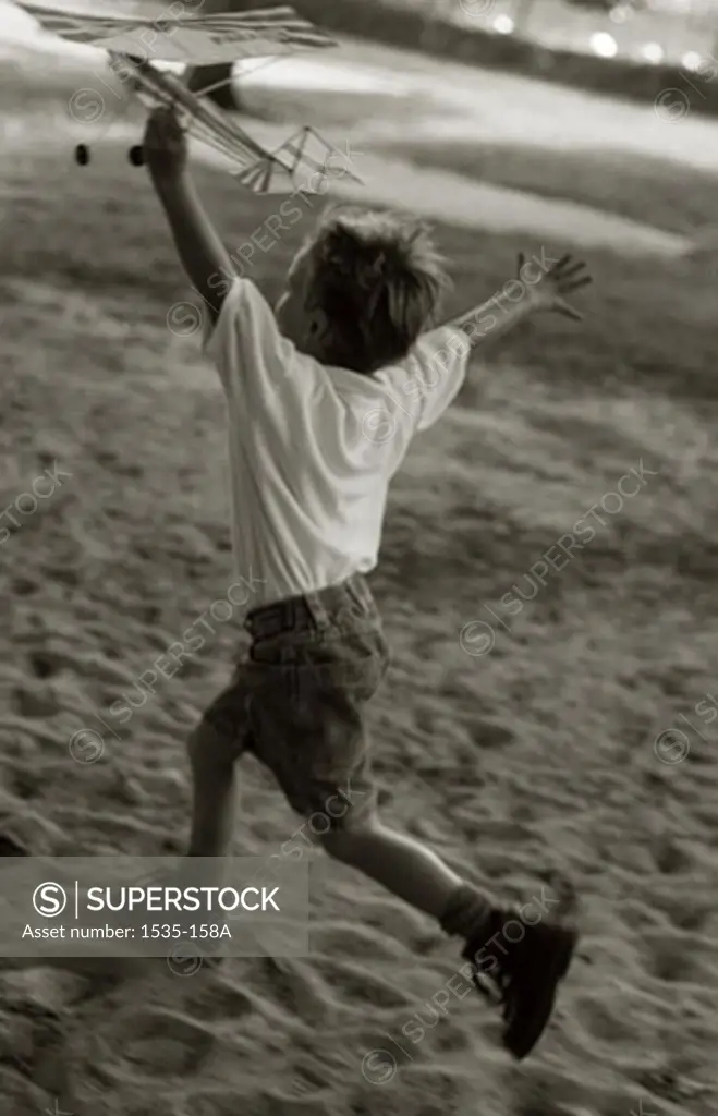 Boy running with a toy airplane