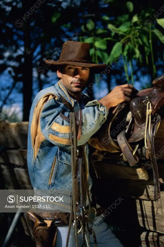 Side profile of a cowboy carrying a saddle