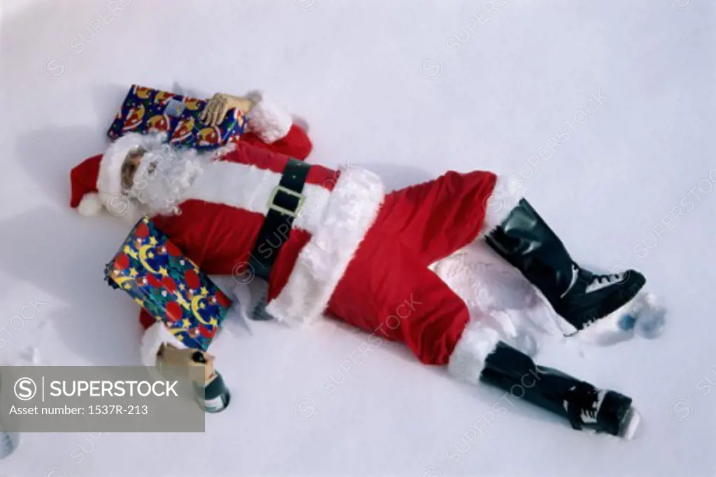 Santa Claus lying down in snow with gifts