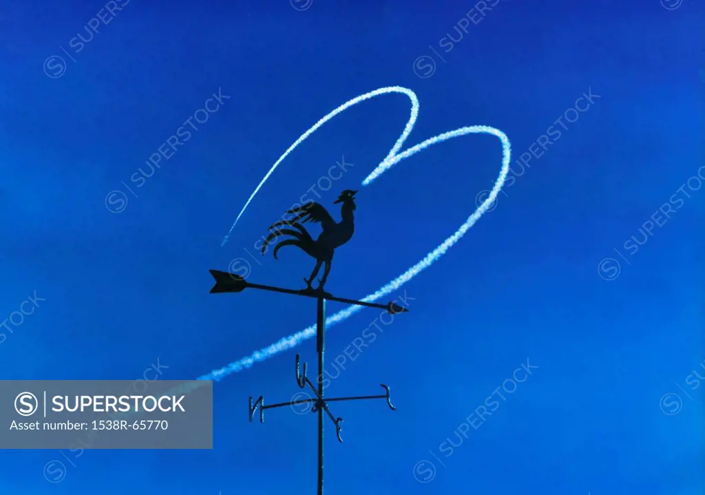 Weather vane against heart shaped vapour trail