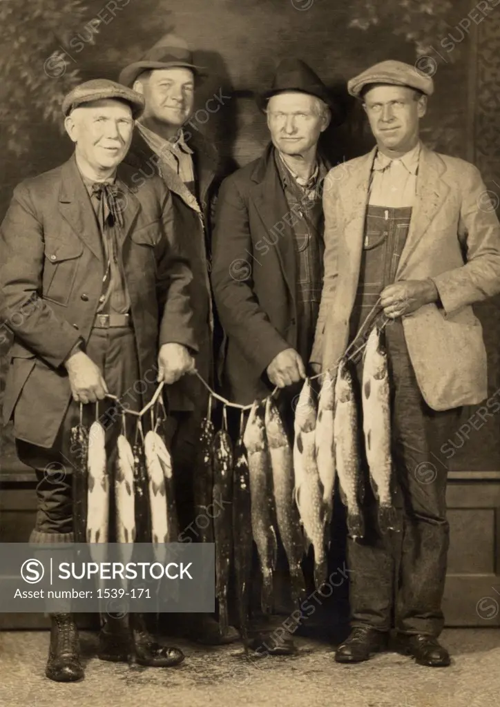 Portrait of a group of men holding dead fish, c. 1920