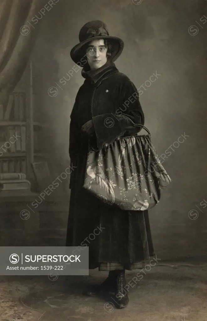Portrait of a mid adult woman standing with a bag, 1910