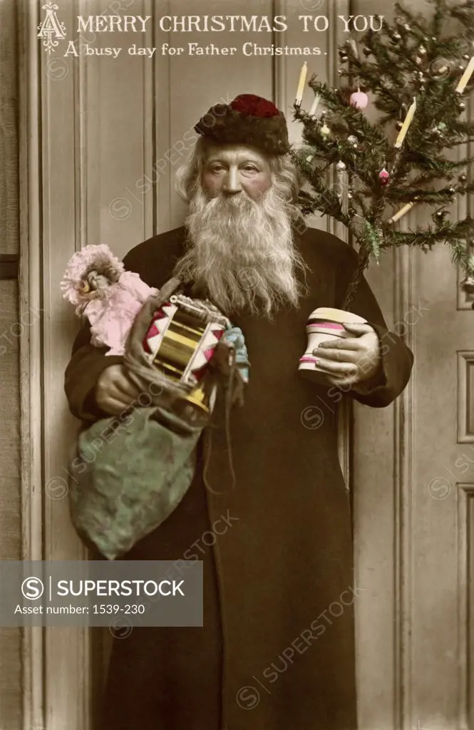 Santa Claus carries an armload of gifts and a Christmas tree postcardc. 1910
