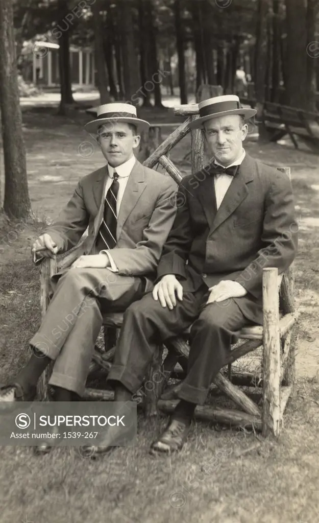 two men sitting on rustic tree-limb bench c.1910