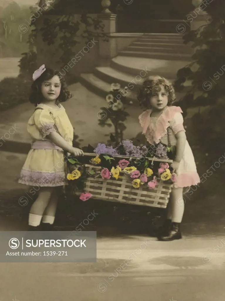 Hand colored postcard of two girls carrying a basket of flowers, Europe, 1910