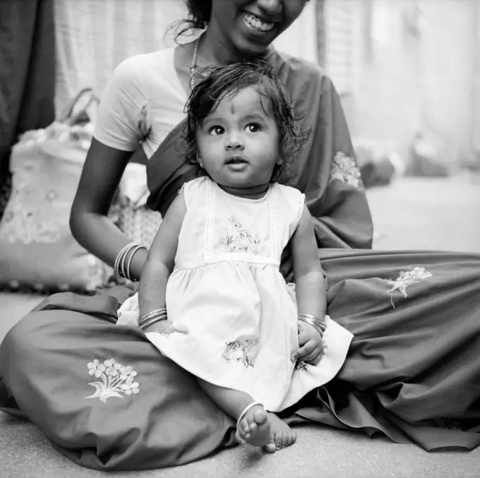 South Asian Indian Girl Child sitting on Mothers lap ; India