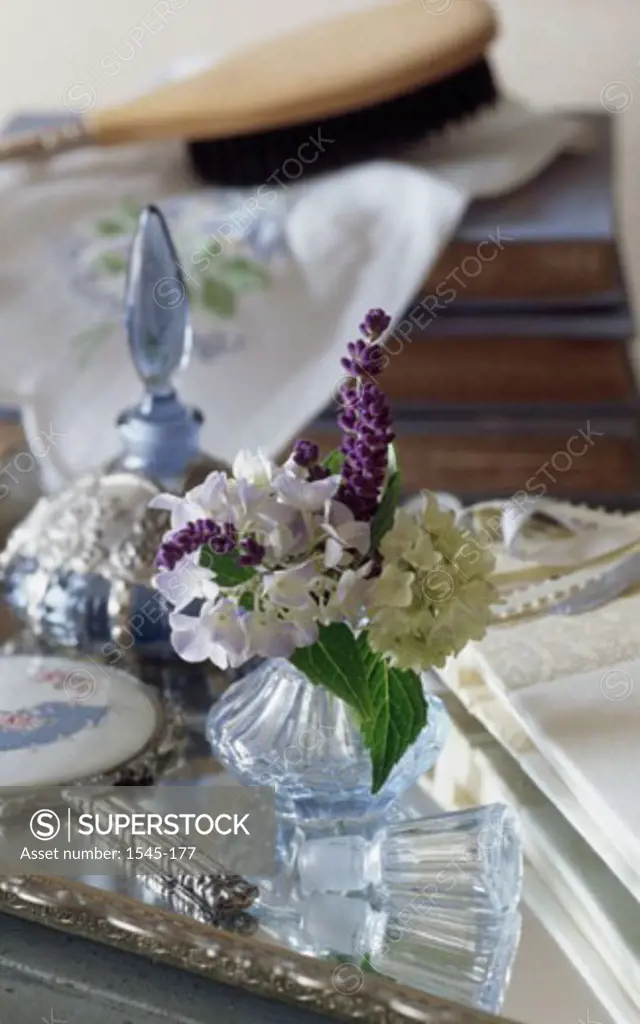 Close-up of perfume bottles and a hand mirror with a flower vase on a table
