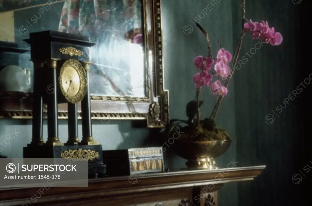 Close-up of a clock with a flower vase on a mantelpiece