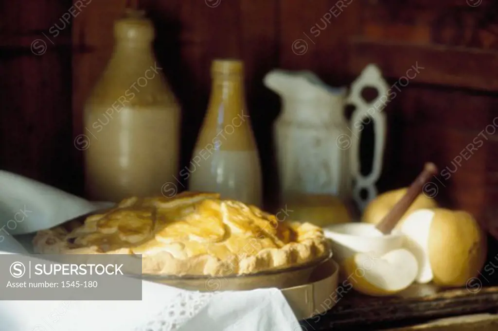 Close-up of an apple pie with bottles and a jug