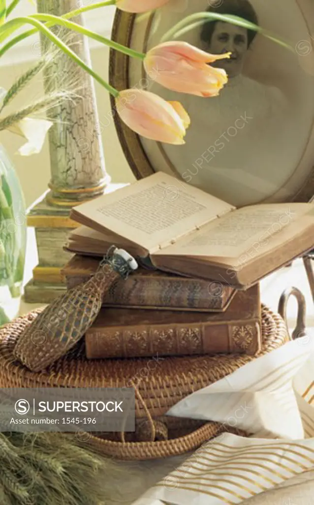 Close-up of books with a bottle on a wicker basket