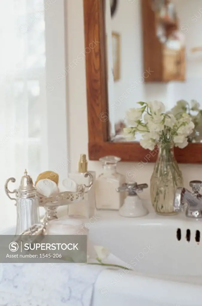Close-up of a flower vase with toiletries on a bathroom sink