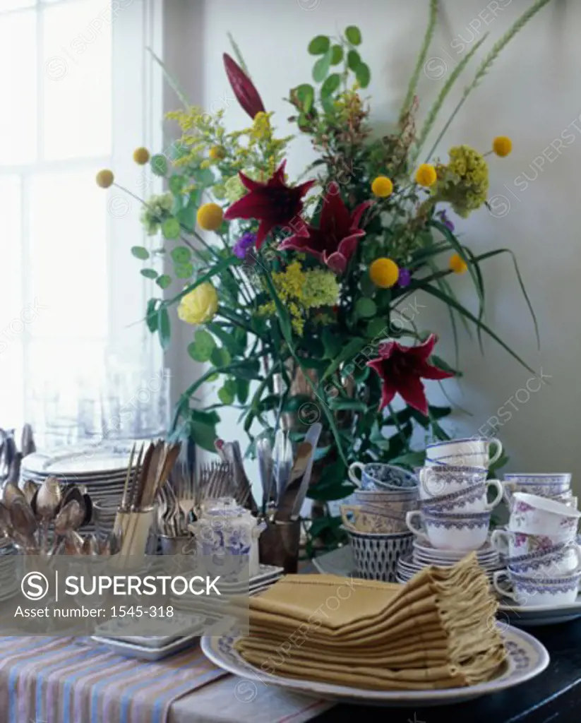Close-up of kitchen utensils with flowers in a vase on a table