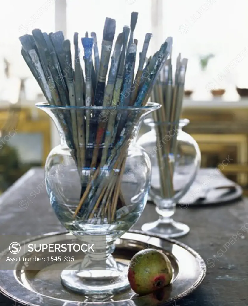 Close-up of paintbrushes in jars on a tray