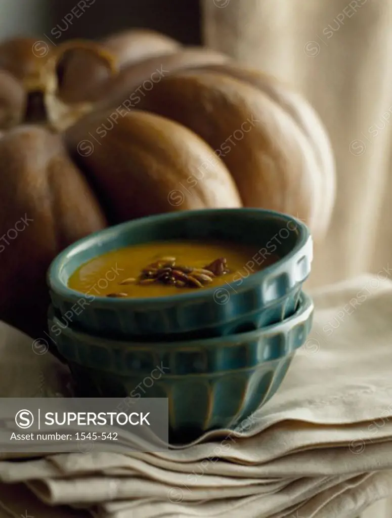 Close-up of a bowl of soup with a pumpkin behind it