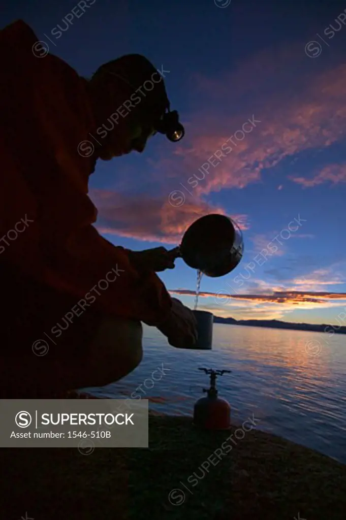 Silhouette of a hiker preparing food at the lakeside, Lake Tahoe, Nevada, USA
