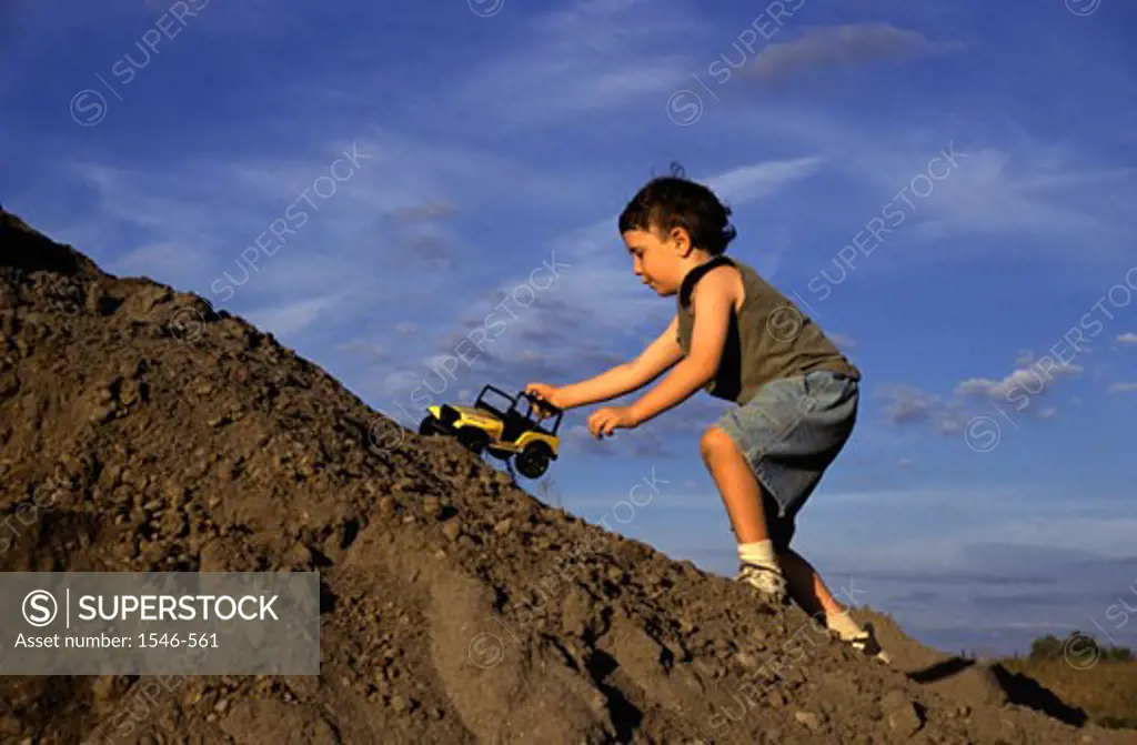 Boy playing with a toy car on a hill