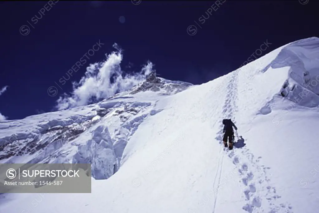 Rear view of a person climbing a snow covered mountain