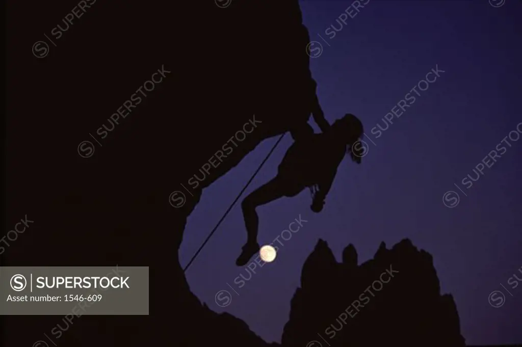 Silhouette of a person climbing a mountain